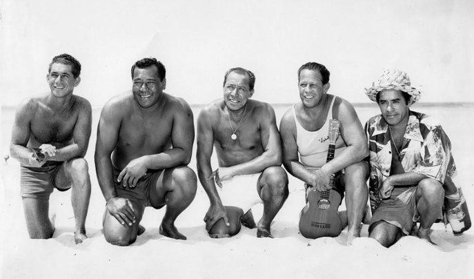 5 men crouched on the beach